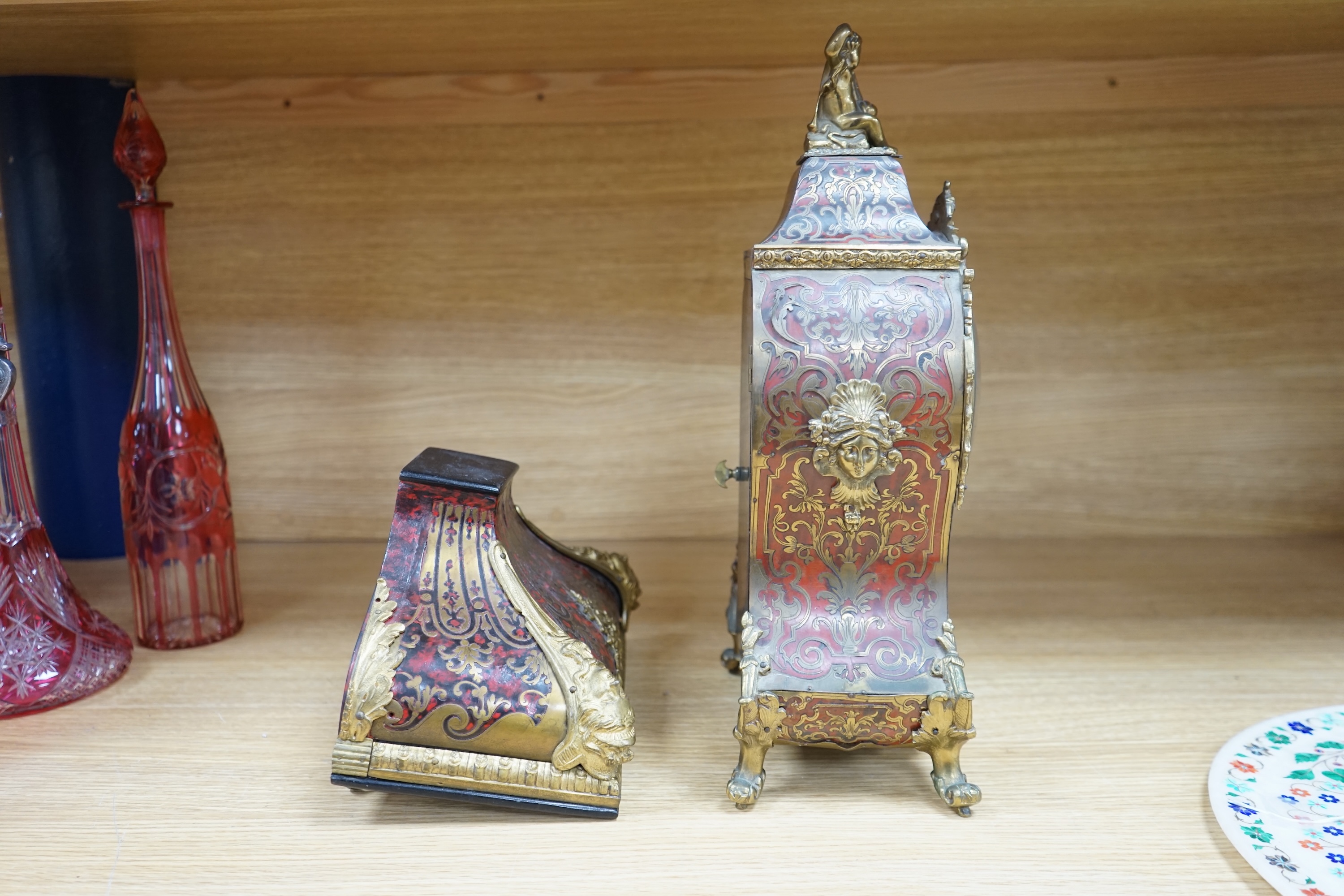 A French scarlet Boulle clock, and original bracket, the waisted case with glass front enclosing boulle interior and sunburst pendulum, c. 1860, clock 42cm high. Condition - fair, untested